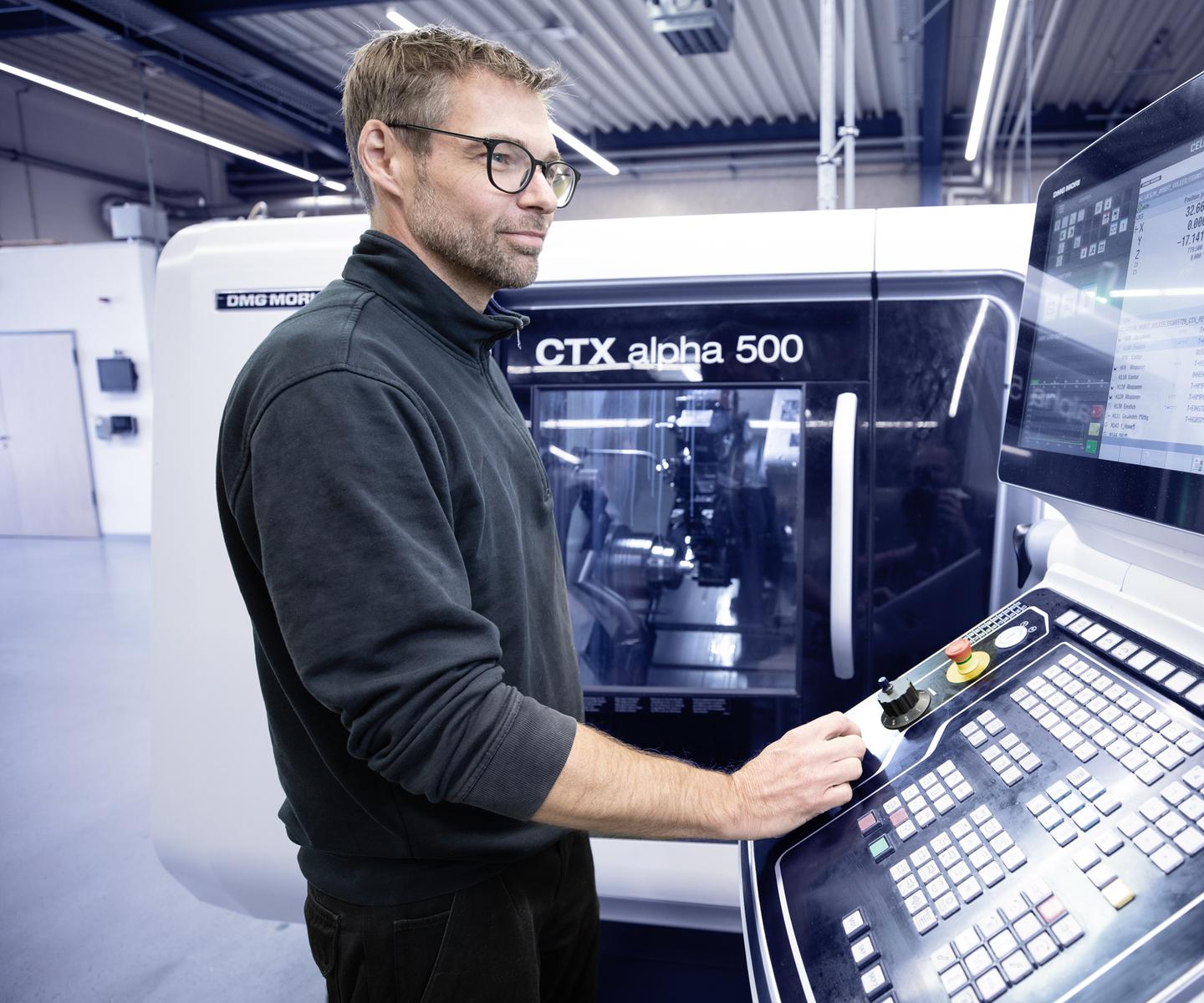 Ein Mann steuert eine CNC-Maschine CTX alpha 500 und betrachtet das Display mit Steuerungsinformationen.