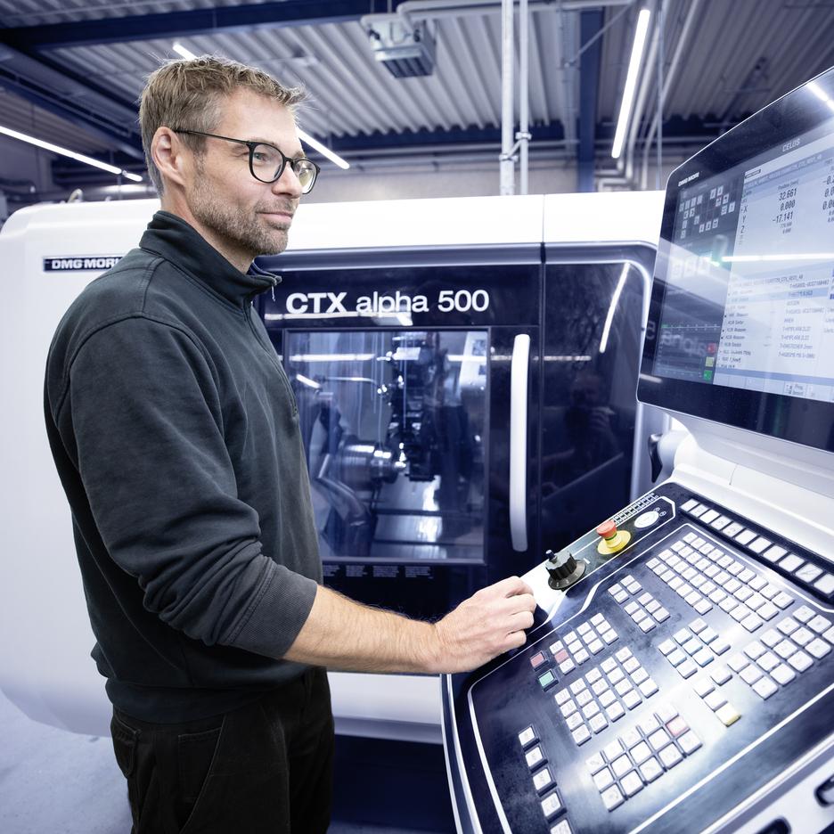 Ein Mann steuert eine CNC-Maschine CTX alpha 500 und betrachtet das Display mit Steuerungsinformationen.