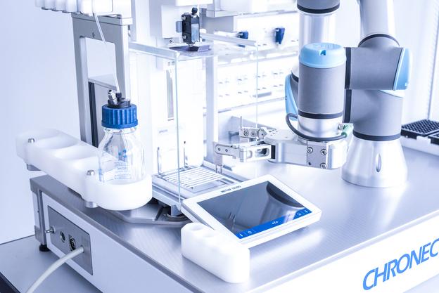 Close-up of a laboratory measuring device with a pipette, a screen, and a bottle on a table.