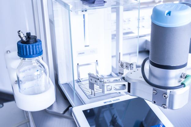 Nahaufnahme eines automatisierten Laborgeräts mit einem Behälter und einem Display für präzise Messungen.