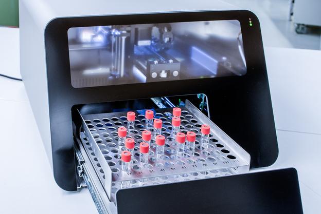 Laborger&auml;t mit einer Schublade, die mehrere Probenr&ouml;hrchen mit roten Verschl&uuml;ssen enth&auml;lt.