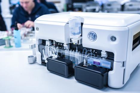 Nahaufnahme eines medizinischen Ger&auml;ts mit transparenten Schl&auml;uchen, Flaschen und Kassette auf einem Tisch.