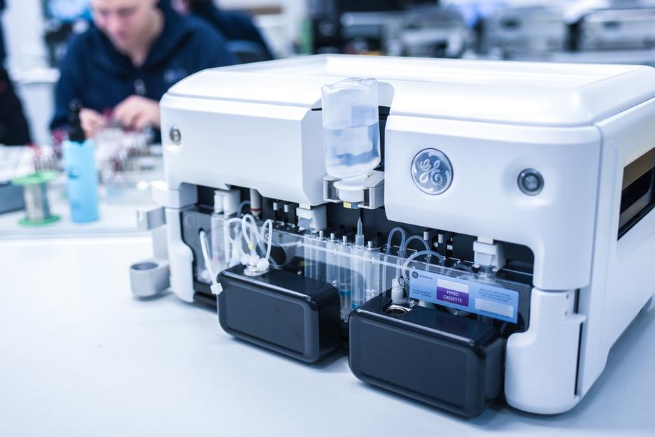 Nahaufnahme eines medizinischen Ger&auml;ts mit transparenten Schl&auml;uchen, Flaschen und Kassette auf einem Tisch.