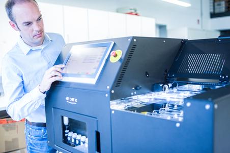 Man operating an HIDEX device with a touchscreen display in a modern laboratory.